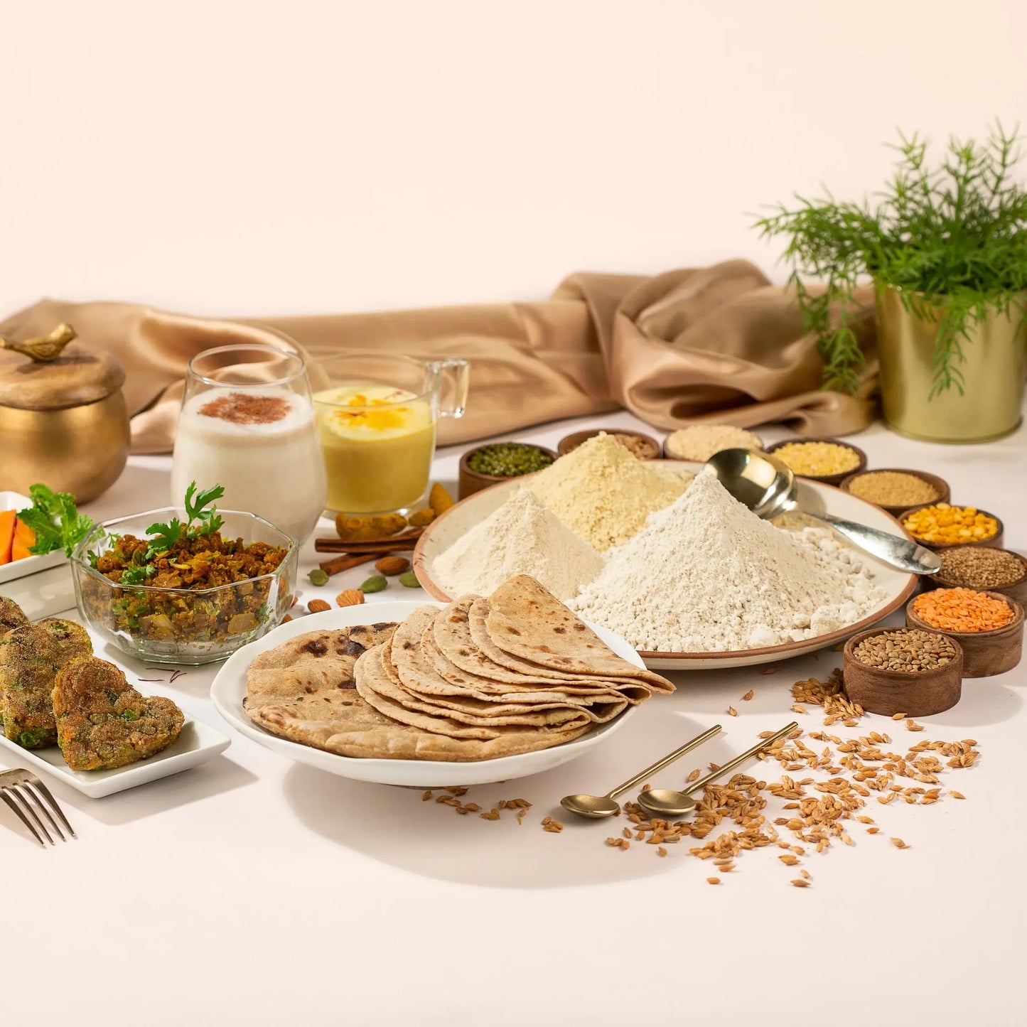 Assorted Indian food items including rotis, flour, and spices on a light background